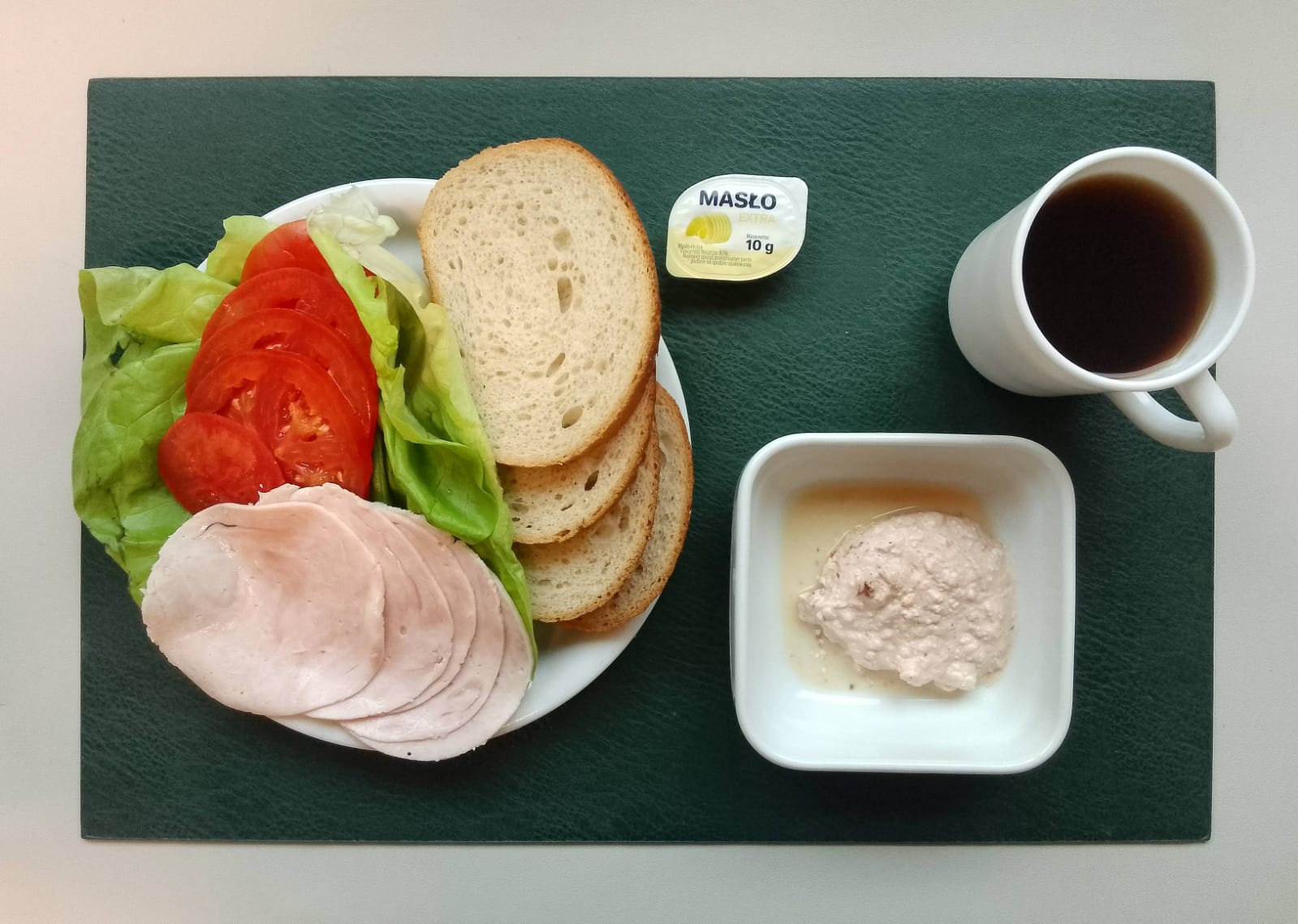 Chleb mieszany pszenno-żytni 80 g ( GLU PSZ, GLU ŻYT, ) Masło porcjowane 10g (82% tł.) 1 szt ( MLE,) Twarożek pomidorowy + 50 g ( MLE,) Szynkowa dębowa drobiowa kiełbasa grubo rozdrobniona 50 g Plastry pomidora + 100 g Sałata zielona 20 g Herbata czarna ekspresowa z cytryną Cateringowa b/c 250 ml Cukier 5 g