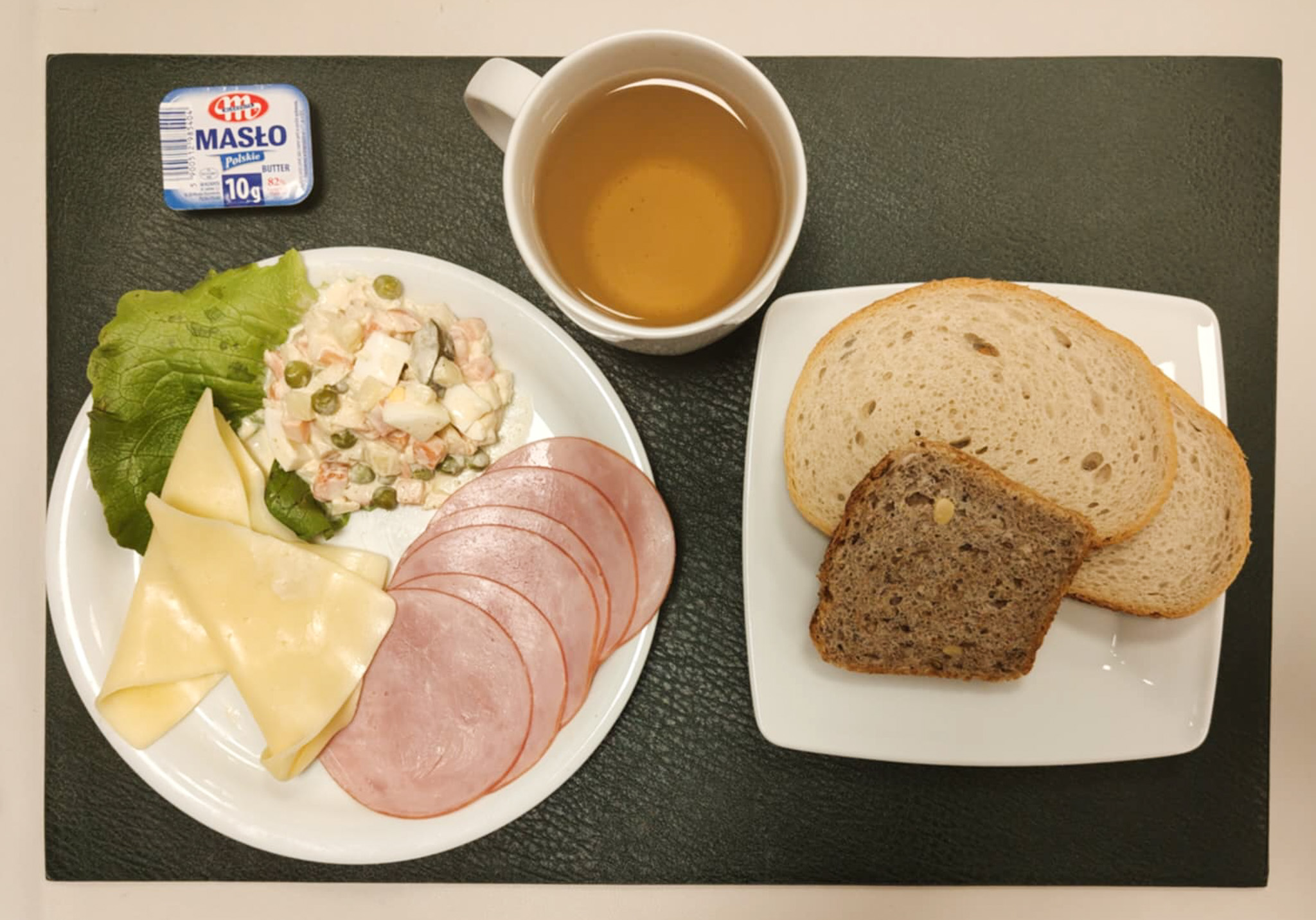 Chleb mieszany pszenno-żytni 50 g ( GLU PSZ, GLU ŻYT, ) Chleb wieloziarnisty 30 g ( GLU PSZ, SOJ, SEZ, GLU ŻYT, ) Masło porcjowane 10g (82% tł.) 2 szt ( MLE,) Ser żółty 30 g (MLE,) Szynkowa dębowa kieł.wp.gr.rozd.wędz.parzo.z dodat.wody w osł.niejad 50 g Sałatka jarzynowa z jajkiem + 120 g ( JAJ, MLE, SEL, GOR, ) Sałata zielona 10 g Herbata czarna ekspresowa z cytryną Cateringowa b/c 250 ml Cukier 5 g