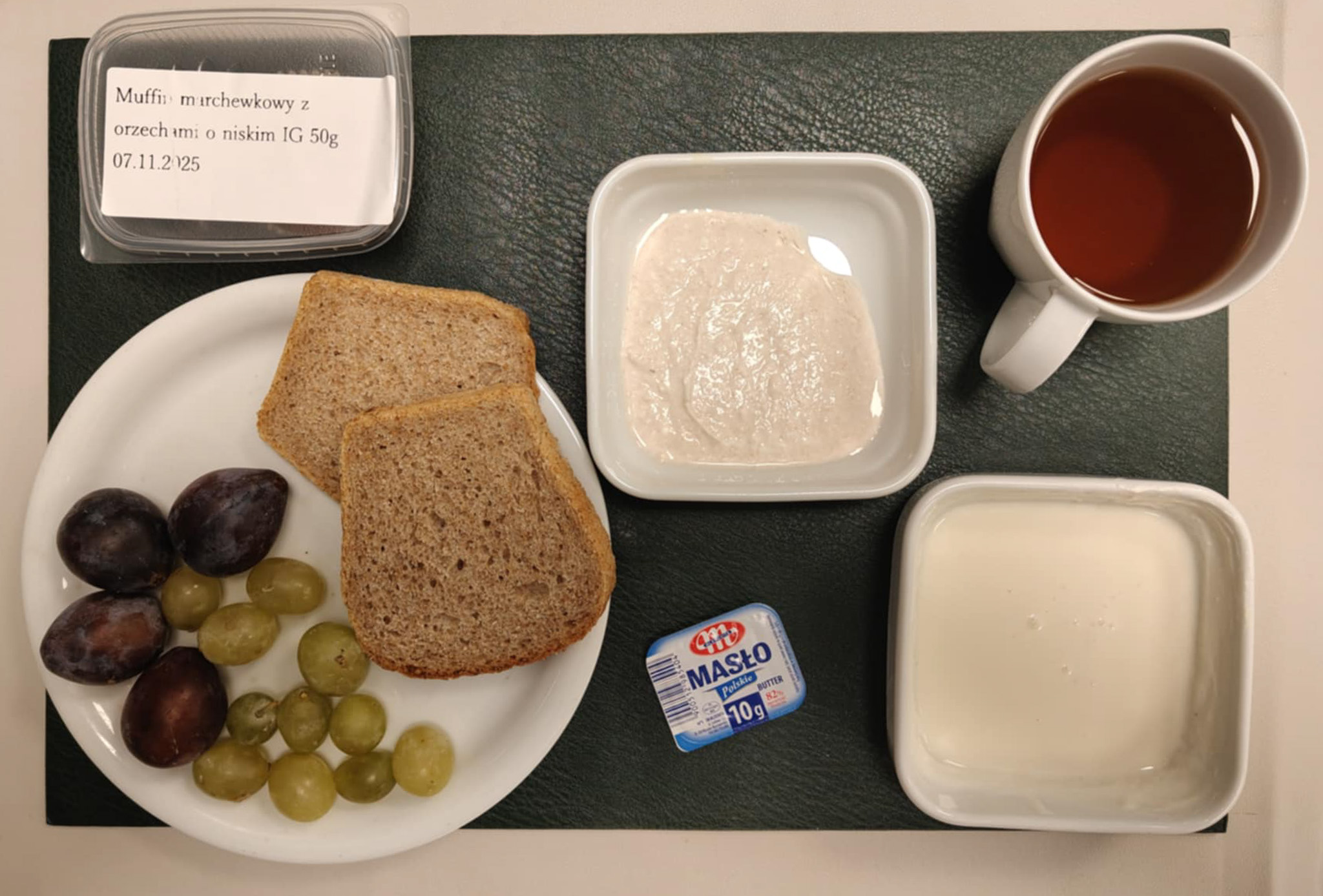 Muffin marchewkowy z orzechami o niskim IG 50g 1 szt ( GLU PSZ, JAJ, MLE, ORZ, może zawierać: SOJ,) Chleb Graham 60 g ( GLU PSZ,) Masło porcjowane 10g (82% tł.) 1 szt ( MLE,) Twarożek różany + 50 g ( MLE,) Jogurt waniliowy + 100 g ( MLE,) Śliwka 60 g Winogrona 60 g Herbata czarna ekspresowa z cytryną Cateringowa b/c 250 ml Cukier 5 g