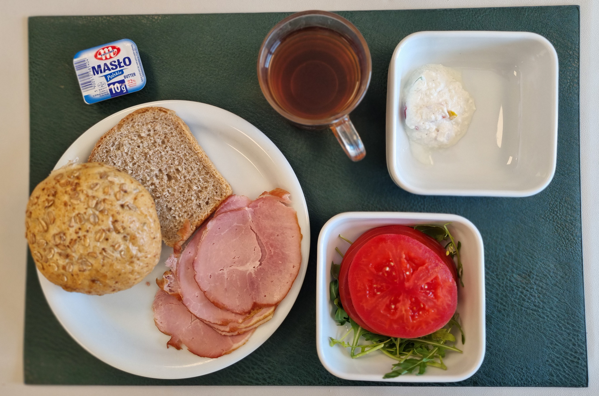 Bułka pszenna wieloziarnista 50g 1 szt ( GLU PSZ, GLU ŻYT, ) Chleb Graham 30 g ( GLU PSZ,) Masło porcjowane 10g (82% tł.) 1 szt ( MLE,) Szynka od Zduna-wędzonka wieprzowa,szynka wędzona,parzona 50 g Twarożek z kolorową papryką + 50 g ( MLE,) Plastry pomidora + 110 g Rukola 10 g Herbata czarna ekspresowa z cytryną Cateringowa b/c 250 ml