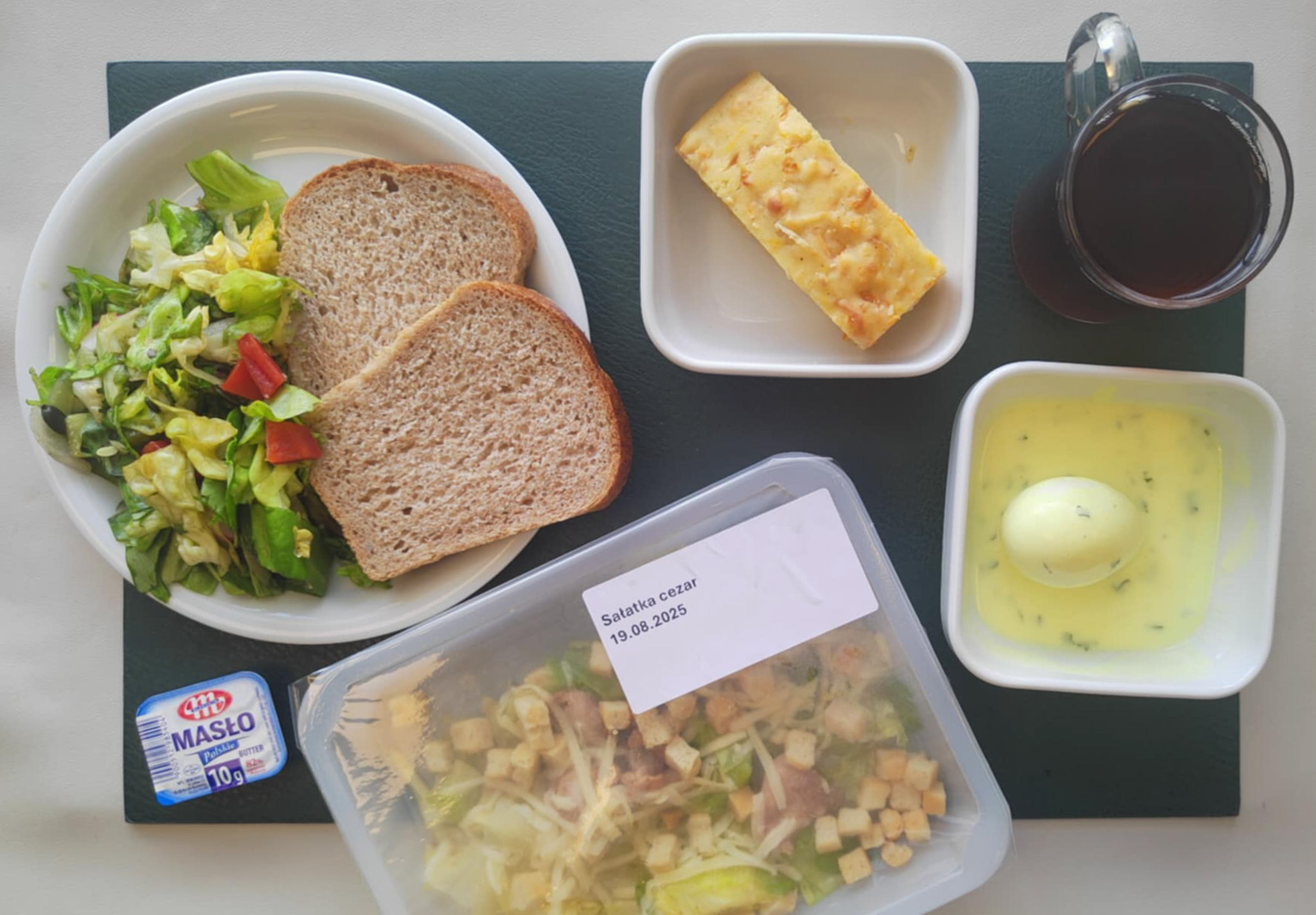 Wytrawny placek z mozzarellą i warzywami + 75 g ( GLU PSZ, JAJ, MLE, ) Chleb Graham 60 g (GLU PSZ,) Masło porcjowane 10g (82% tł.) 1 szt ( MLE,) Jajko w sosie jogurtowo-pietruszkowym + 100 g ( JAJ, MLE,) Sałatka wiosenna z dressingiem + 120 g ( SOJ,) Herbata czarna ekspresowa z cytryną Cateringowa b/c 250 m