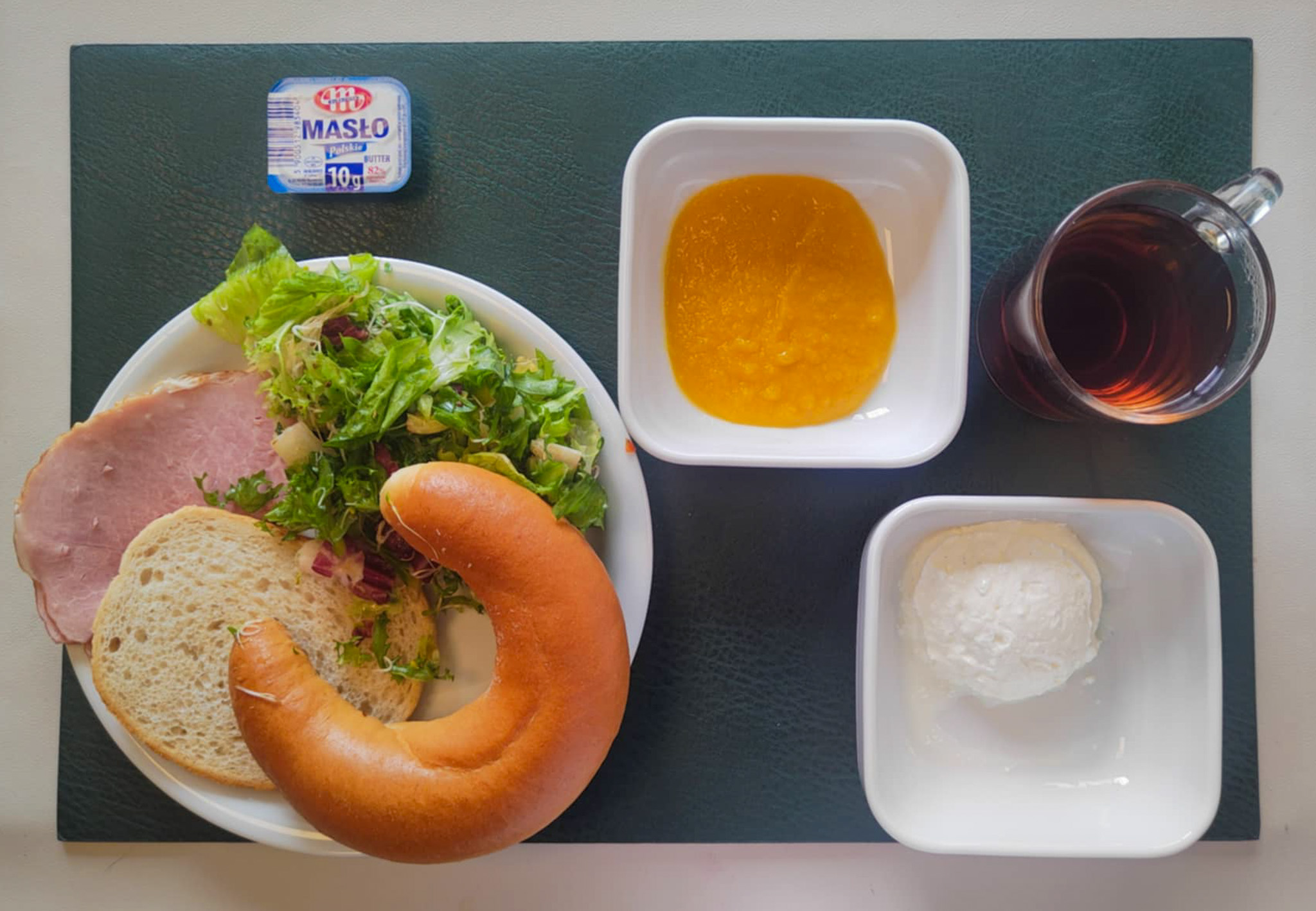 Rogal drożdżowy 50g 1 szt ( GLU PSZ, MLE, GLU ŻYT, ) Chleb mieszany pszenno-żytni 25 g ( GLU PSZ, GLU ŻYT,) Masło porcjowane 10g (82% tł.) 1 szt ( MLE,) Szynka od Zduna-wędzonka wieprzowa,szynka wędzona,parzona 50 g Twarożek domowy waniliowy + 50 g ( MLE, może zawierać: GLU PSZ, JAJ, OZI, SOJ, MLE, ORZ, SEZ, ) Mus bananowy z jabłkami i mango + 100 g Mix sałat z olejem i kiełkami lucerny + 120 g Herbata czarna ekspresowa z cytryną Cateringowa z/c 250 ml