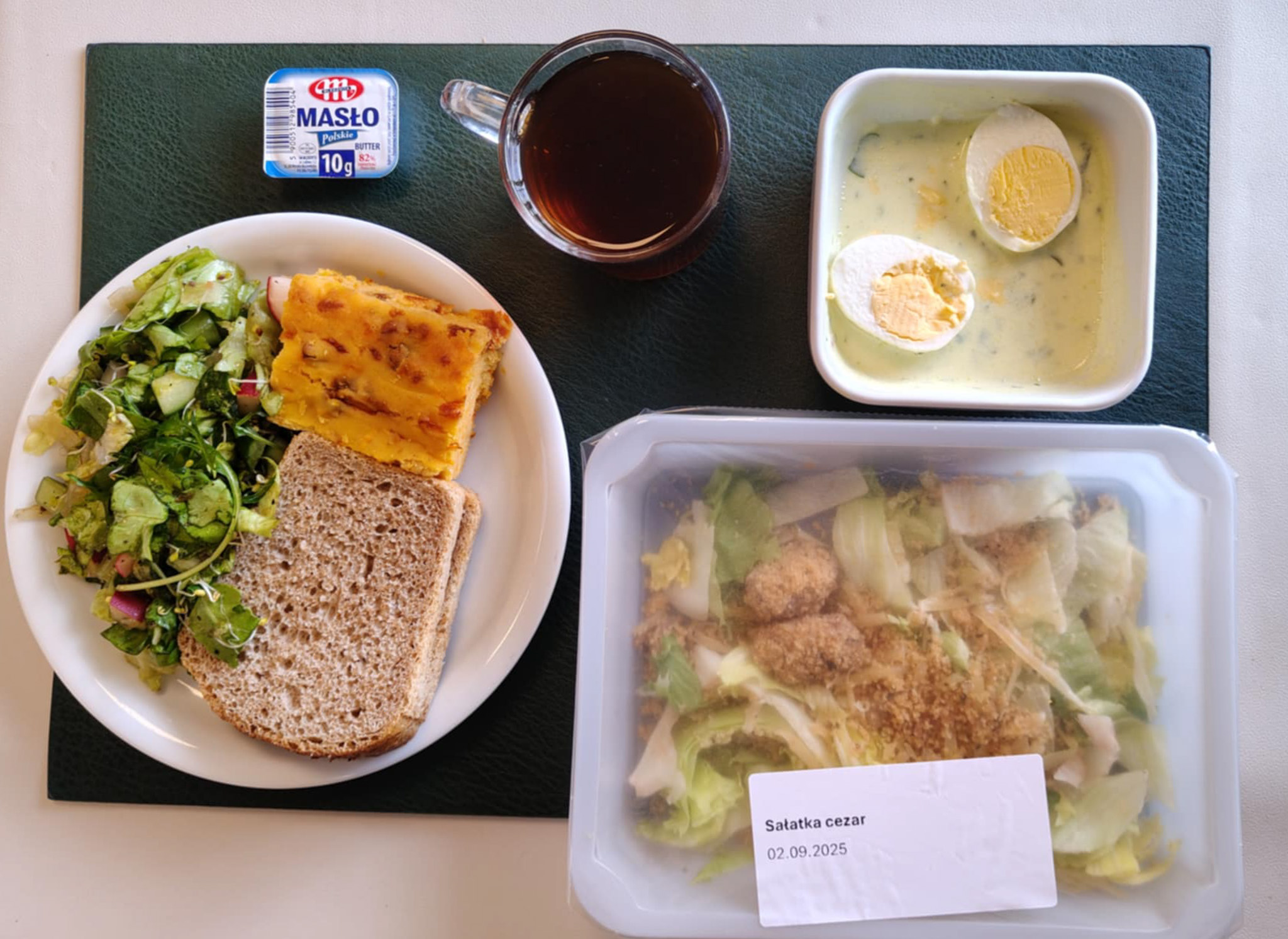 Wytrawny placek z mozzarellą i warzywami + 75 g ( GLU PSZ, JAJ, MLE, ) Chleb Graham 60 g (GLU PSZ,) Masło porcjowane 10g (82% tł.) 1 szt ( MLE,) Jajko w sosie jogurtowo-pietruszkowym + 100 g ( JAJ, MLE,) Sałatka wiosenna z dressingiem + 120 g ( SOJ,) Herbata czarna ekspresowa z cytryną Cateringowa b/c 250 ml