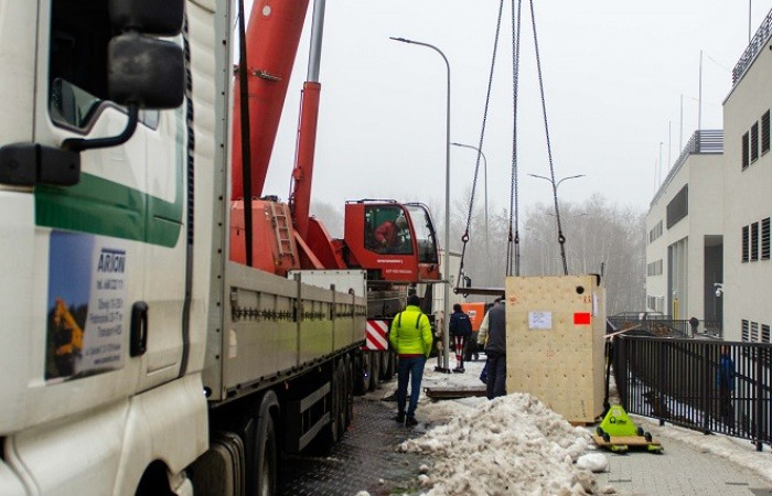 Zbliżenie na tira oraz pracowników dostawy przed budynkiem szpitala 