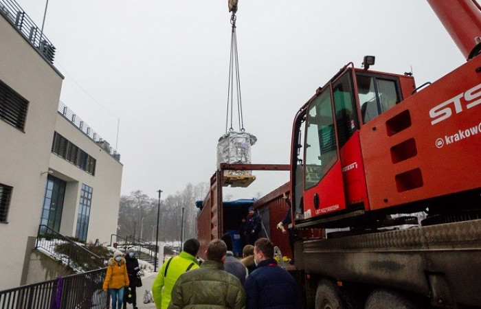 Zbliżenie na dźwig oraz pracowników dostawy przed wejściem do szpitala 